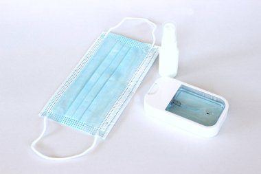 Covid-19 kavramının önlenmesi: Beyaz arkaplanda maske ve alkol spreyi