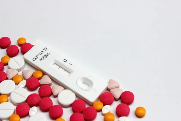 Positive test result of Covid-19 antigen test kit and drug tablets on the white background