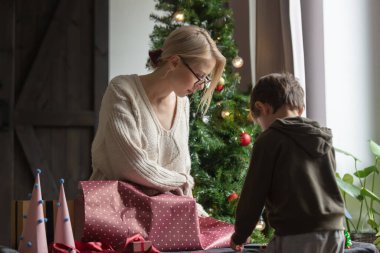 Anne ve oğlu evde Noel hediyelerini paketliyor. 