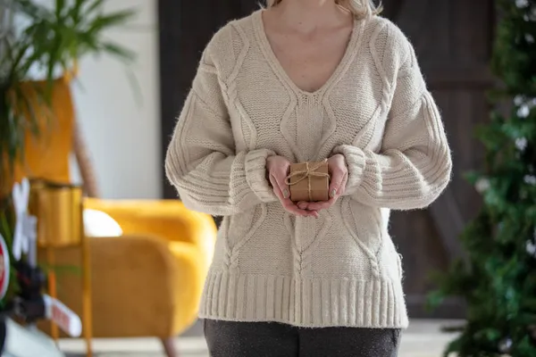 セーターの女性は自宅でギフトボックスを保持します — ストック写真