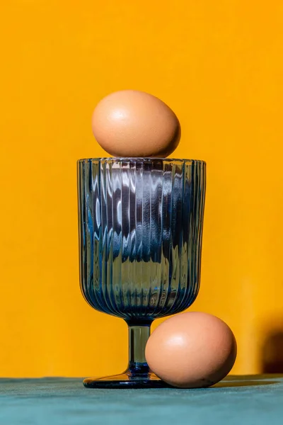 Two Eggs Glass Blue Table Yellow Background — Foto de Stock