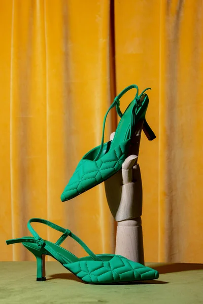 Ahşap Sarı Perde Arkasında Yeşil Topuklu Ayakkabı Tutuyor — Stok fotoğraf