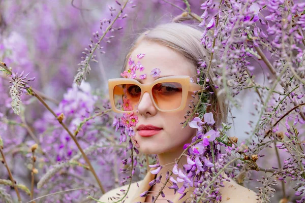 美しいサングラスの女性と藤の木の枝が咲く周りに花の花びら — ストック写真