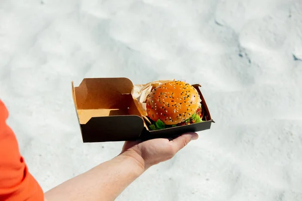 Mężczyzna Trzymać Pudełko Hamburgerem Plaży Piaskiem Tle — Zdjęcie stockowe