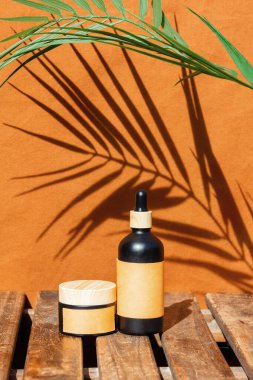 Arkaplanda palmiye ağacı olan ahşap bir masanın üzerinde krema kabı.