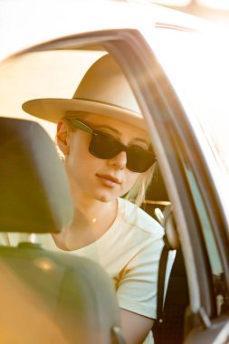 Şapkalı şık bir kadın. Arabada yolcu gibi oturuyor.