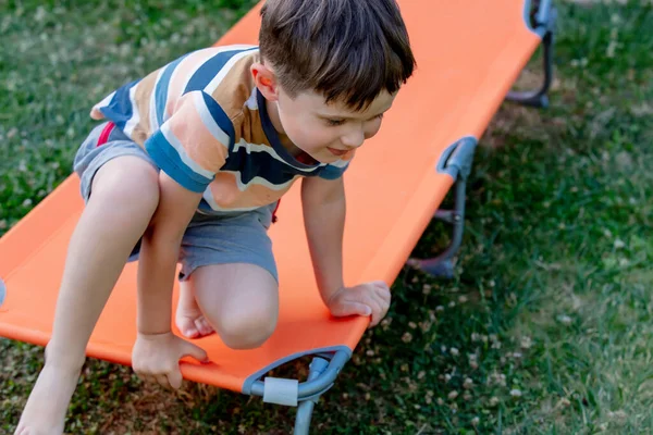 Kleiner Junge Sitzt Auf Orangefarbener Sonnenliege Freien — Stockfoto