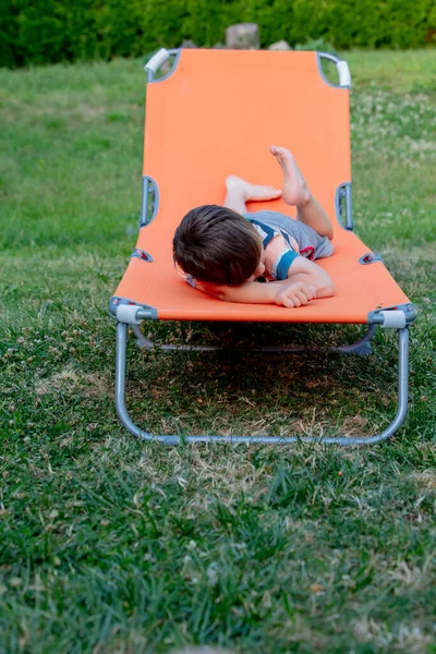 Niño Sienta Una Tumbona Naranja Aire Libre — Foto de Stock