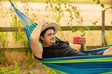 hamakta cep telefonu kullanan adam