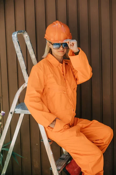 Stylish Woman Orange Suit Hardhat Sunglasses Next Stairs Brown Background — Fotografia de Stock