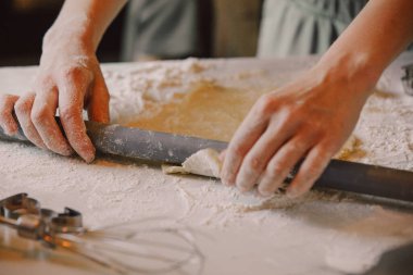 Closeup view on hands how mother with son preparing flour for cookies in the kitchen