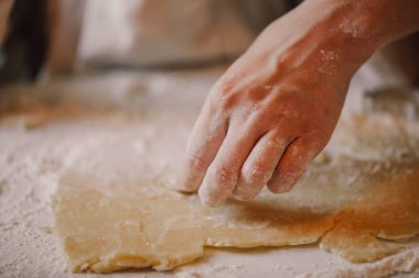 Closeup view on hands how mother with son preparing flour for cookies in the kitchen