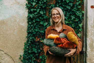 Woman in brown shirt hold handmade fabric pumpkins as decoration for Halloween holiday