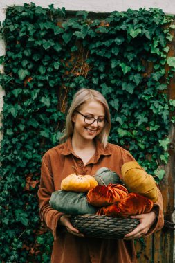 Woman in brown shirt hold handmade fabric pumpkins as decoration for Halloween holiday