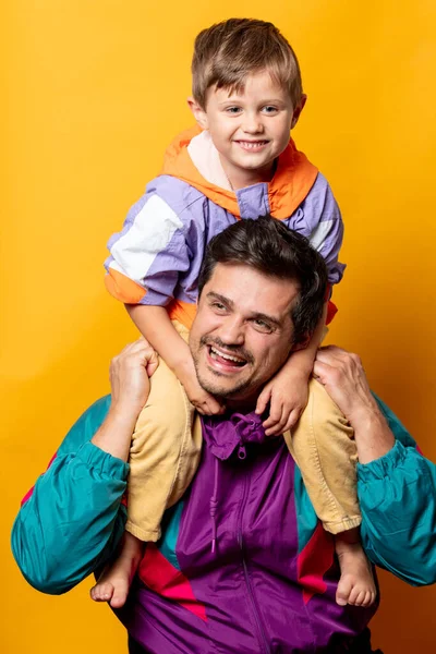 Father with son in 80s vintage sport suits on yellow background