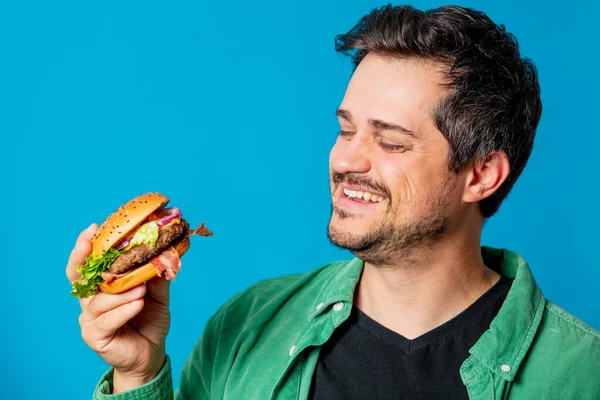 Usmívající Bílý Chlap Zelené Košili Hamburgerem Modrém Pozadí — Stock fotografie