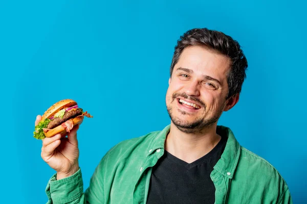 Glimlachende Blanke Man Groen Shirt Met Hamburger Blauwe Achtergrond — Stockfoto