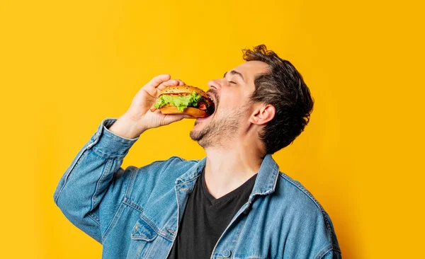 Hongerige Man Met Hamburger Gele Achtergrond — Stockfoto