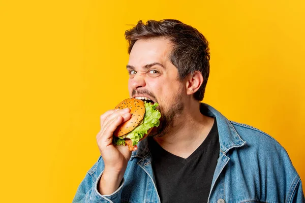 Hongerige Man Met Hamburger Gele Achtergrond — Stockfoto