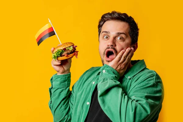 Překvapený Muž Hamburgerem Německou Vlajkou Žlutém Pozadí — Stock fotografie