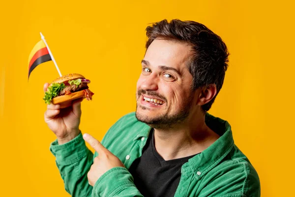 Usmívající Muž Hamburgerem Německou Vlajkou Žlutém Pozadí — Stock fotografie