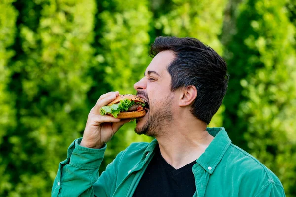 穿着绿色衬衫 户外有汉堡包的人 — 图库照片