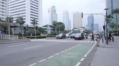 Jakarta, Endonezya-16 Ocak 2022: Güney Jakarta 'daki Bundaran Hotel Endonezya' da işlek bir yolda kavşağı geçen personel. 4K