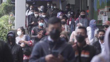 Jakarta, Endonezya-06 Mart 2022: Ağır çekim Tren yolcuları koruyucu maskeler takarak Jakarta 'nın Dukuh Atas tren istasyonundan çıkıyorlar.