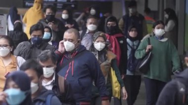 Jakarta, Endonezya-06 Mart 2022: Ağır çekim Tren yolcuları koruyucu maskeler takarak Jakarta 'nın Dukuh Atas tren istasyonundan çıkıyorlar.