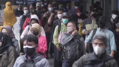 Jakarta, Endonezya-06 Mart 2022: Ağır çekim Tren yolcuları koruyucu maskeler takarak Jakarta 'nın Dukuh Atas tren istasyonundan çıkıyorlar.