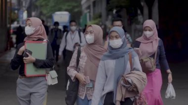 Jakarta, Endonezya-06 Mart 2022: Ağır çekim Tren yolcuları koruyucu maskeler takarak Jakarta 'nın Dukuh Atas tren istasyonundan çıkıyorlar.