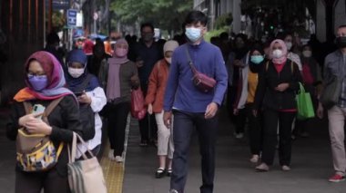 Jakarta, Endonezya-06 Mart 2022: Ağır çekim Tren yolcuları koruyucu maskeler takarak Jakarta 'nın Dukuh Atas tren istasyonundan çıkıyorlar.