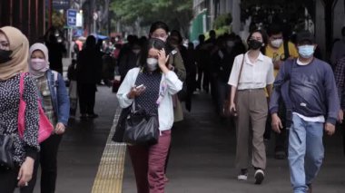 Jakarta, Endonezya-06 Mart 2022: Ağır çekim Tren yolcuları koruyucu maskeler takarak Jakarta 'nın Dukuh Atas tren istasyonundan çıkıyorlar.