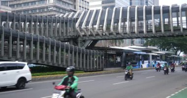 Jakarta, Endonezya - 11 Nisan 2022: Sudirman Caddesi, Jakarta, Endonezya 'daki Gelora Bung Karno yaya köprüsünden geçen insanlar. 4K çözünürlüğü