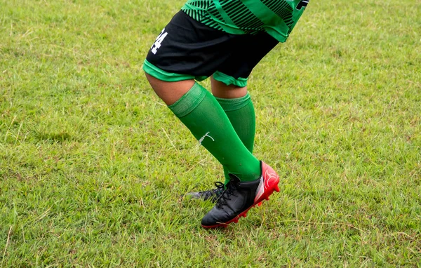 Futbol ayakkabısı giyen futbolcu seçici bir odak ile çimenlerde yürüyor..