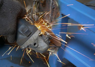 Worker grinding metal with grinding machine. Sparks when grinding iron