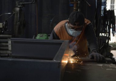 Jakarta, Indonesia - July 10, 2022: Asian people are doing iron welding work. Sparks coming out of the welder