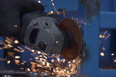 Worker grinding metal with grinding machine. Sparks when grinding iron