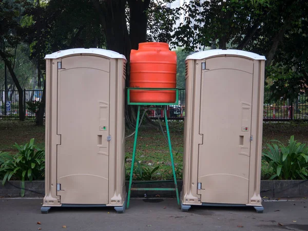 Two portable outdoor toilets with garden background