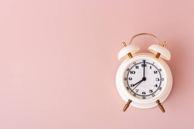 Pembe arkaplan konumundaki beyaz alarmlı saat