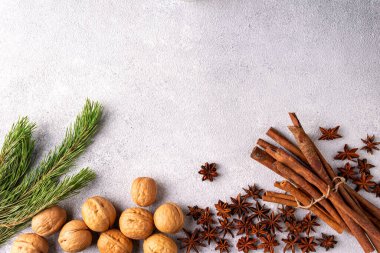 Tarçın çubukları yıldız anason fındıkları ve çam dalları gri alçıda yatıyor.