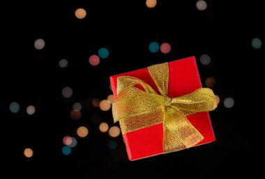 Koyu arkaplanda altın kurdeleli kırmızı kutu, bokeh