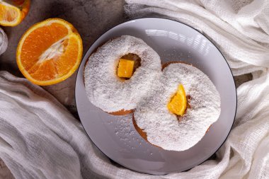 Beyaz bir tabakta sekiz şekilli portakal kabuklu çörek serpiştirilmiş hindistan cevizi var..