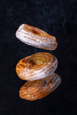 Krema ve kremalı çörekler koyu bir arka planda, seçici odak