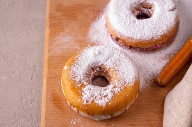 Donutlar, üzerine pudra şekeri serpiştirilmiş, tahtanın üzerine uzanmış.