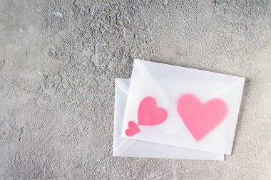 Gri alçılı şeffaf zarfın içindeki kırmızı kağıt kalpler, boşluğu kopyala