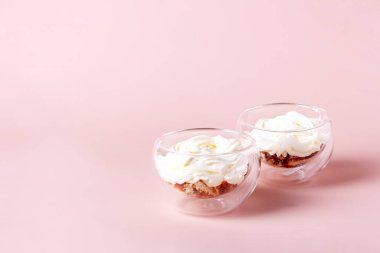 Bej arka planda cam bir fincanda iki porsiyon tiramisu, seçici odaklanma.