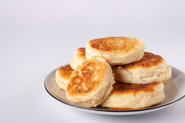 Beyaz zemin üzerinde beyaz seramik tabakta süzme peynirli kekler, yakın plan.