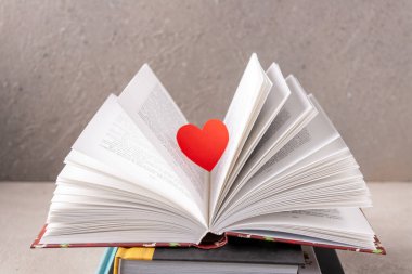 kırmızı kağıt bir kalp açık bir kitabın üzerinde süzülür, seçici bir odak