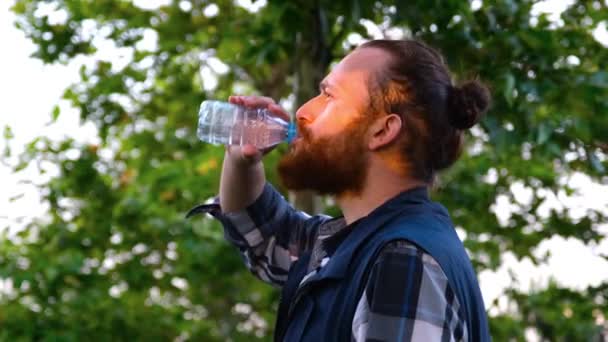 Питьевая вода, кавказский мужчина пьет воду в парке — стоковое видео